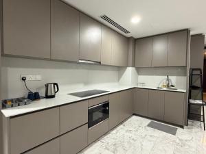 una cucina con armadi grigi e banconi bianchi di Eaton Premier Suite KLCC a Kuala Lumpur
