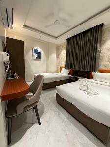 AkalkotHotel Aishwarya的有两张床和一张书桌的酒店房间