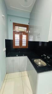 a white kitchen with a sink and a window at Diya Apartment in Rishīkesh