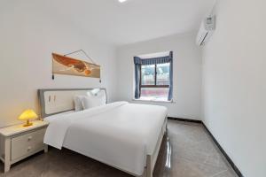 een witte slaapkamer met een wit bed en een raam bij 张家界博亭安屿设计师民宿 in Zhangjiajie