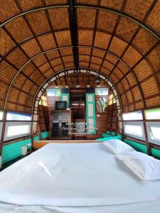 a large white bed in a room with windows at p1 เรือนเรือรักษ์ เรือนรอยน้ำ บ้านกามเทพ อัมพวา โฮมสเตย์ in Amphawa