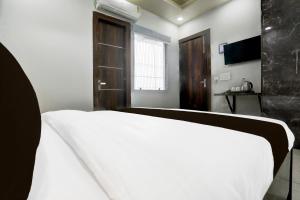 a bedroom with a white bed and a window at Hotel O Shivoham in Indirapuram