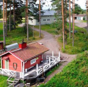 a small red house with a red roof next to a road at KoloCabins - Hiitolanjoki 1 in Simpele