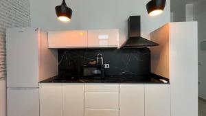 Una cocina con gabinetes blancos y una encimera negra. en Salabert Suite, en Valencia 7 fotos más