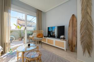 a living room with a television and a surfboard at Beach & City Center Apartment Campello in El Campello