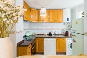 a kitchen with wooden cabinets and a white dishwasher at Beach & City Center Apartment Campello in El Campello