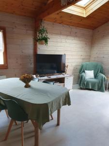 a living room with a table and a tv and a chair at Le petit chalet de campagne in Richeling