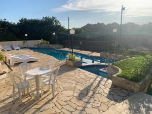 a patio with a table and chairs next to a pool at Casa 6 Mares de Búzios - 5 minutos a pé da Rua das Pedras in Búzios