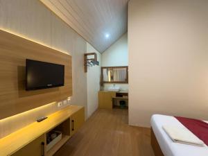 a bedroom with a bed and a television on a wall at Rautani Sembalun in Sembalun Lawang
