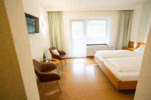 a hotel room with a bed and chairs and a window at Bio-Hotel Upländer Hof in Willingen +23 photos