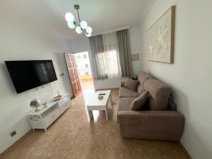 a living room with a couch and a tv at Rincón Del Sol in Frigiliana