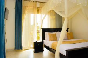 a bedroom with a canopy bed and a window at Kanye Bridge Hotel Jinja in Jinja