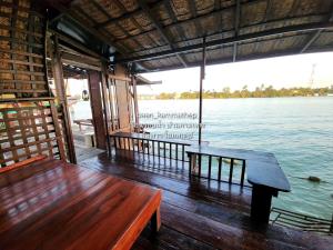 a wooden bench sitting on the deck of a boat at p2 เรือนกระท่อมน้ำ เรือนรอยน้ำ บ้านกามเทพ อัมพวา โฮมสเตย์ in Amphawa