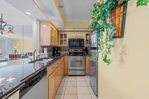 Una cocina con gabinetes de madera y electrodomésticos de acero inoxidable. en Perdido Sun 202, en Perdido Key