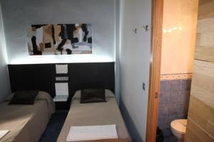 a small room with two beds and a toilet at Hostal Plaza Ruiz in Ceuta