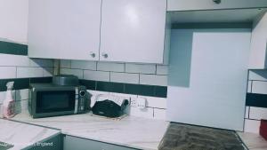 eine Küche mit einer Mikrowelle und einer Tasche auf der Theke in der Unterkunft Private room in Hornchurch London Homestay in Hornchurch