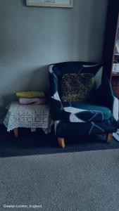 einen blauen Stuhl mit Kissen in einem Zimmer in der Unterkunft Private room in Hornchurch London Homestay in Hornchurch