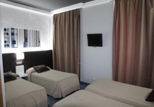 a hotel room with two beds and a television at Hostal Plaza Ruiz in Ceuta