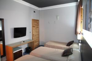 a hotel room with two beds and a television at Hostal Plaza Ruiz in Ceuta