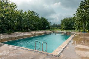 卡尔贾特Teak Resort Karjat的树木繁茂的公园内的游泳池