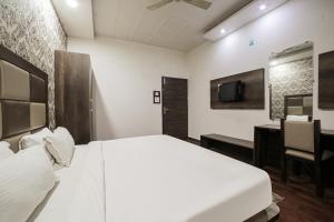 a bedroom with a white bed and a desk and a tv at Townhouse Hollywood Heights in Amritsar