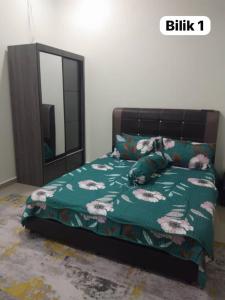 a bed with a green comforter and a mirror at Sofiyyah Homestay in Tumpat +2 photos