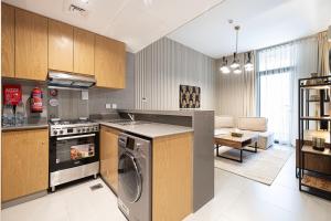 1BR Apartment With Balcony - 9 Mins to Sharjah Airport - Balcony Breeze في الشارقة: مطبخ مع غسالة ملابس وغرفة معيشة +22 صورة