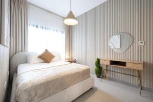 1BR Apartment With Balcony - 9 Mins to Sharjah Airport - Balcony Breeze في الشارقة: غرفة نوم بها سرير ومرآة على الحائط