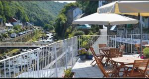 a balcony with chairs and tables and an umbrella at East Lyn House in Lynmouth