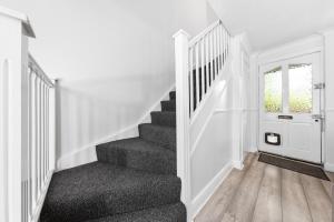 una escalera en una casa con paredes blancas en Watford Cozy Full Home - Perfect for Harry Potter Studios!, en Leavesden Green