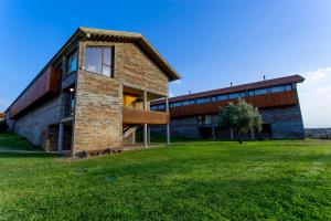 a brick building with a grass field in front of it at Hotel Parque de Monfragüe in Torrejón el Rubio