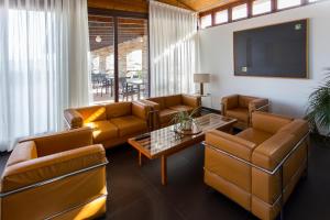 sala de estar con muebles de cuero y TV de pantalla plana en Hotel Parque de Monfragüe, en Torrejón el Rubio