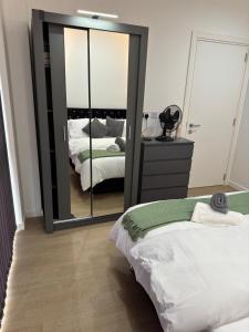 Un dormitorio con dos camas y un gran espejo. en Elegant Apartment in Central Milton Keynes, en Milton Keynes 5 fotos más