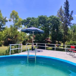 a pool with an umbrella and a table at La rosadita in Chascomús