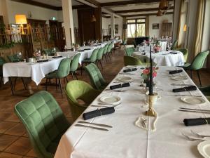 a dining room with white tables and green chairs at Landhaus Müllenborn in Gerolstein