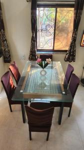 a glass table with chairs and a vase with flowers on it at kareeshmavilla in Mahabaleshwar