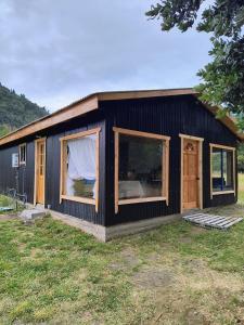 a black house with large windows in a yard at Casa entré Fundos in Lago Ranco