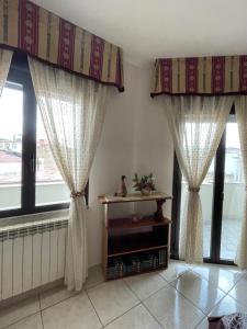 a room with two windows with curtains and a table at Casa San Francesco in Mondragone