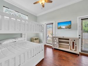 a white bedroom with a bed and a tv at Sandcastle on Castile in Panama City Beach +38 photos