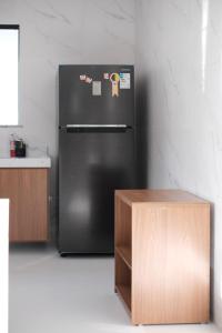 a black refrigerator in a kitchen with a table at Casa Fênix - Casa de Temporada nos Lençóis Maranhenses in Barreirinhas