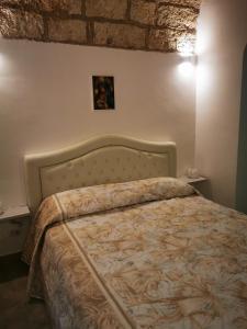 a bed in a bedroom with a brick wall at Maura Domus in Corigliano dʼOtranto +6 photos