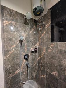 a shower in a bathroom with a marble wall at The Vibs International in Damoh +11 photos