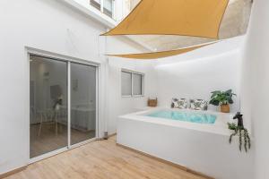 Habitación blanca con baño con bañera grande. en Urban Chic Oasis with AC, Private Pool and Wifi, en Alicante