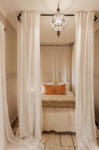 - une chambre dotée d'un lit avec des rideaux blancs et un lustre dans l'établissement Riad Privatif avec Personnel et Services Exclusifs - Kasbah Boma Marrakech I, à Marrakech