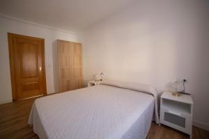 ein Schlafzimmer mit einem weißen Bett und einer Holztür in der Unterkunft Casa Tierra Viva, junto a Bardenas Reales y Sendaviva in Valtierra