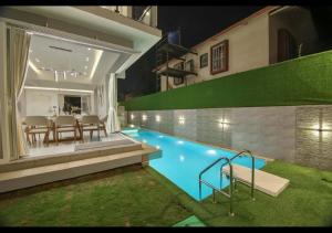 a house with a swimming pool with a table and chairs at Hiaana Villa By Tropicana Stays in Lonavala