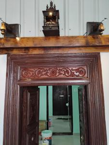 a mirror with a wooden frame with a light above it at Space craft Guest house Heritage villa in kāraikāl