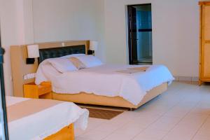 Un dormitorio con dos camas y un espejo. en Quality Inn Motel, Nyanza, en Gahondo