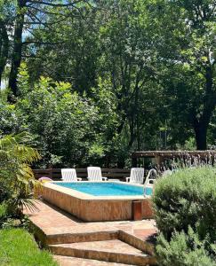 una piscina con 2 sillas de césped y una mesa en Cabañas Das Dorf, en Costa del Este