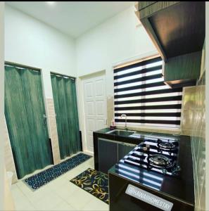 - une cuisine avec une cuisinière et des portes vertes dans l'établissement Kawaii Homestay Kuala Terengganu, à Kuala Terengganu